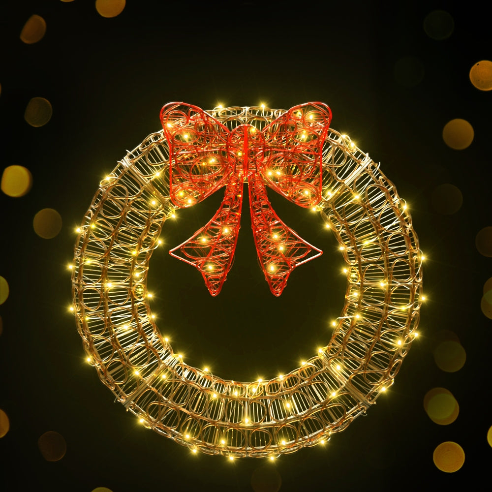 Solar LED wreath with gold wire ring, warm white lights and red ribbon bow
