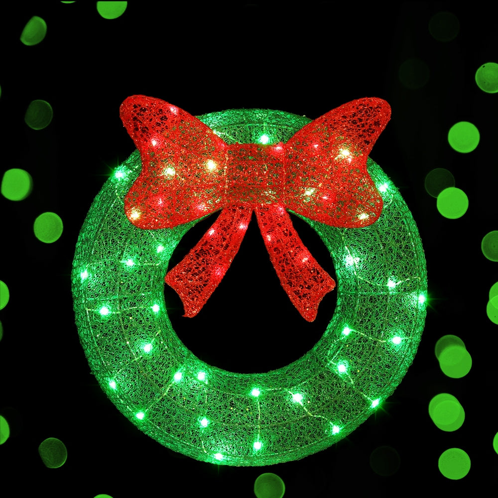 Solar wreath light decoration with red bow and green LED glow on green circular ring