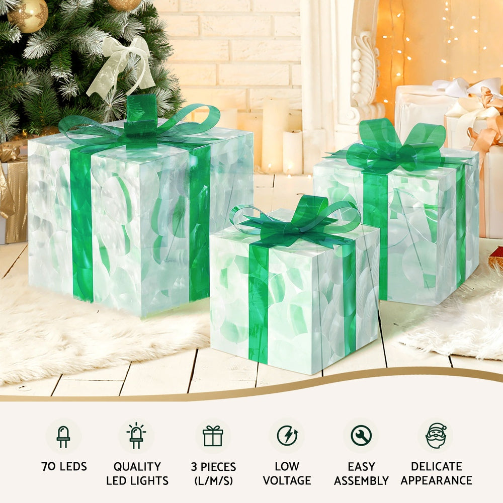 Three clear gift-box LED fairy lights with green ribbons, warm light glow.