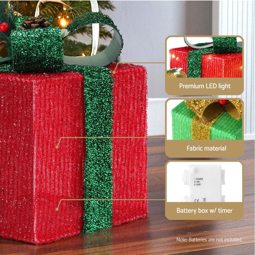 Close-up of red and green fabric gift box fairy lights with ribbon bows and battery box.