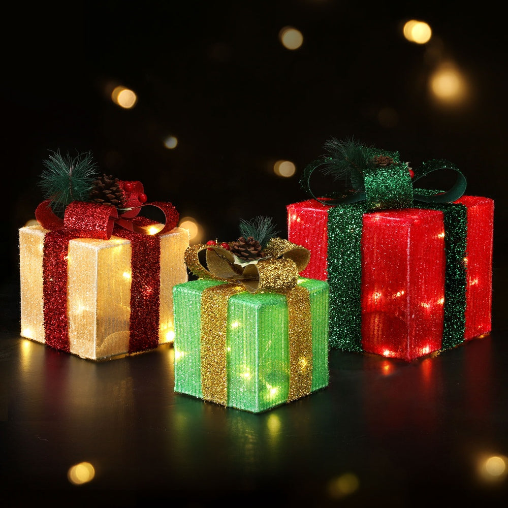 Glowing Christmas gift box fairy lights with ribbon bows in red, green, white, and gold tones.